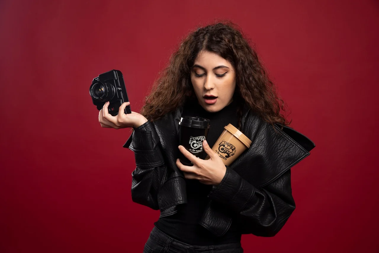 young woman all black outfit holding cup camera